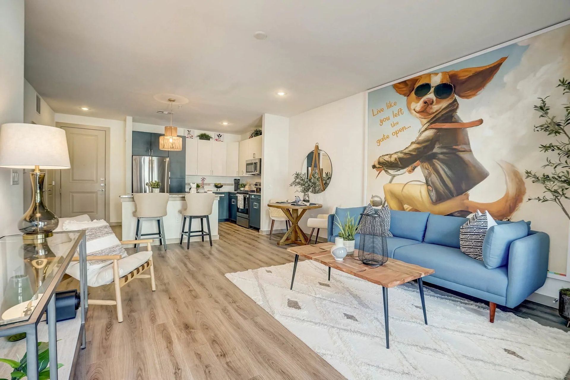 Bright living room with blue sofa, white rug, and large wall mural of a dancing dog