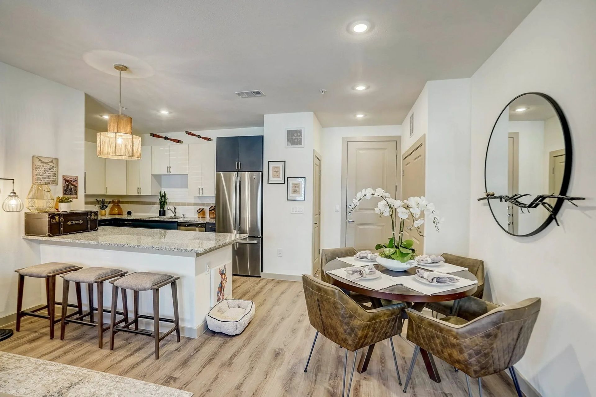 Bright modern kitchen and dining area with white cabinets, island, round table, and wicker chairs