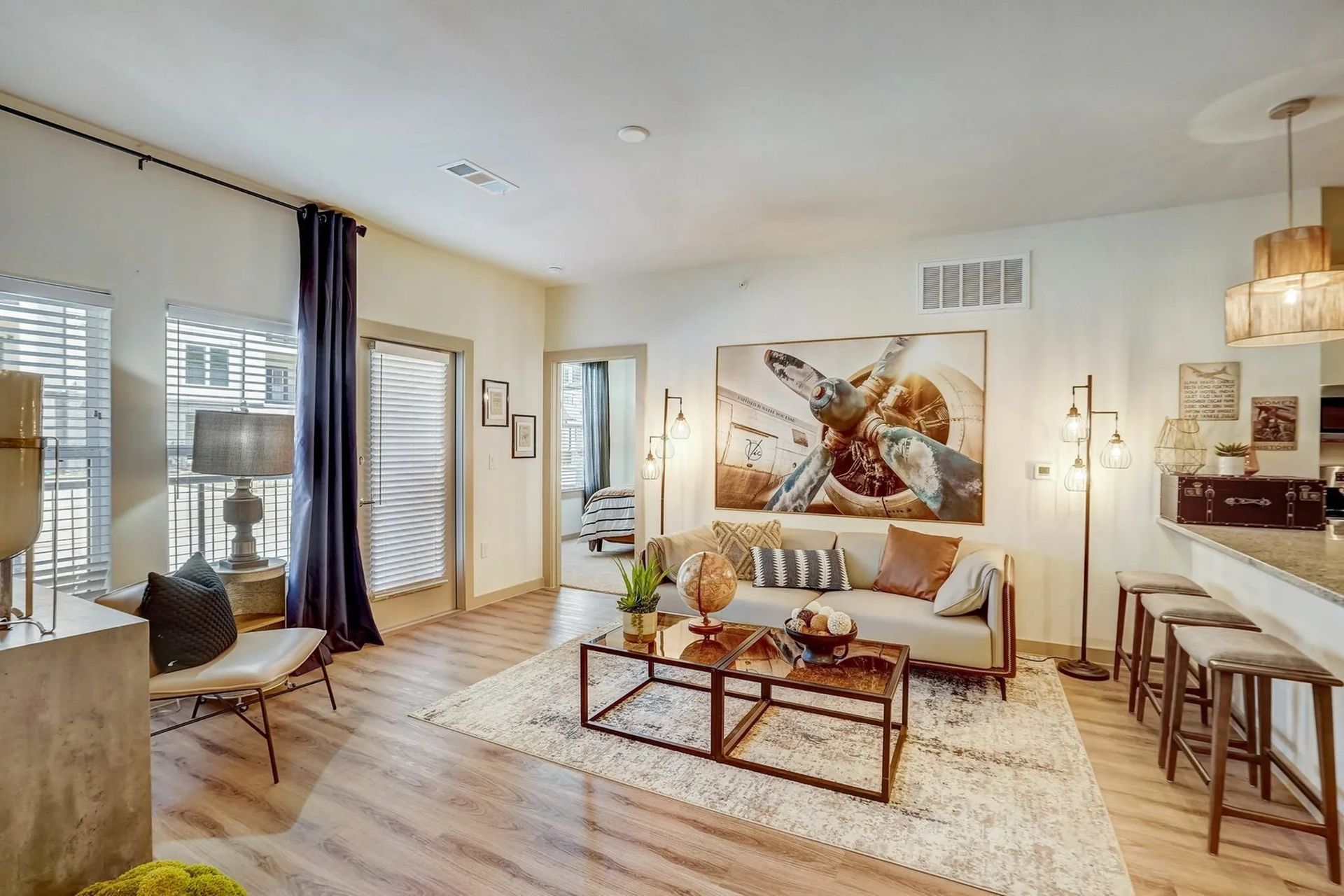 Modern living room with a white sofa, large wall art, coffee table, and balcony doors with purple curtains