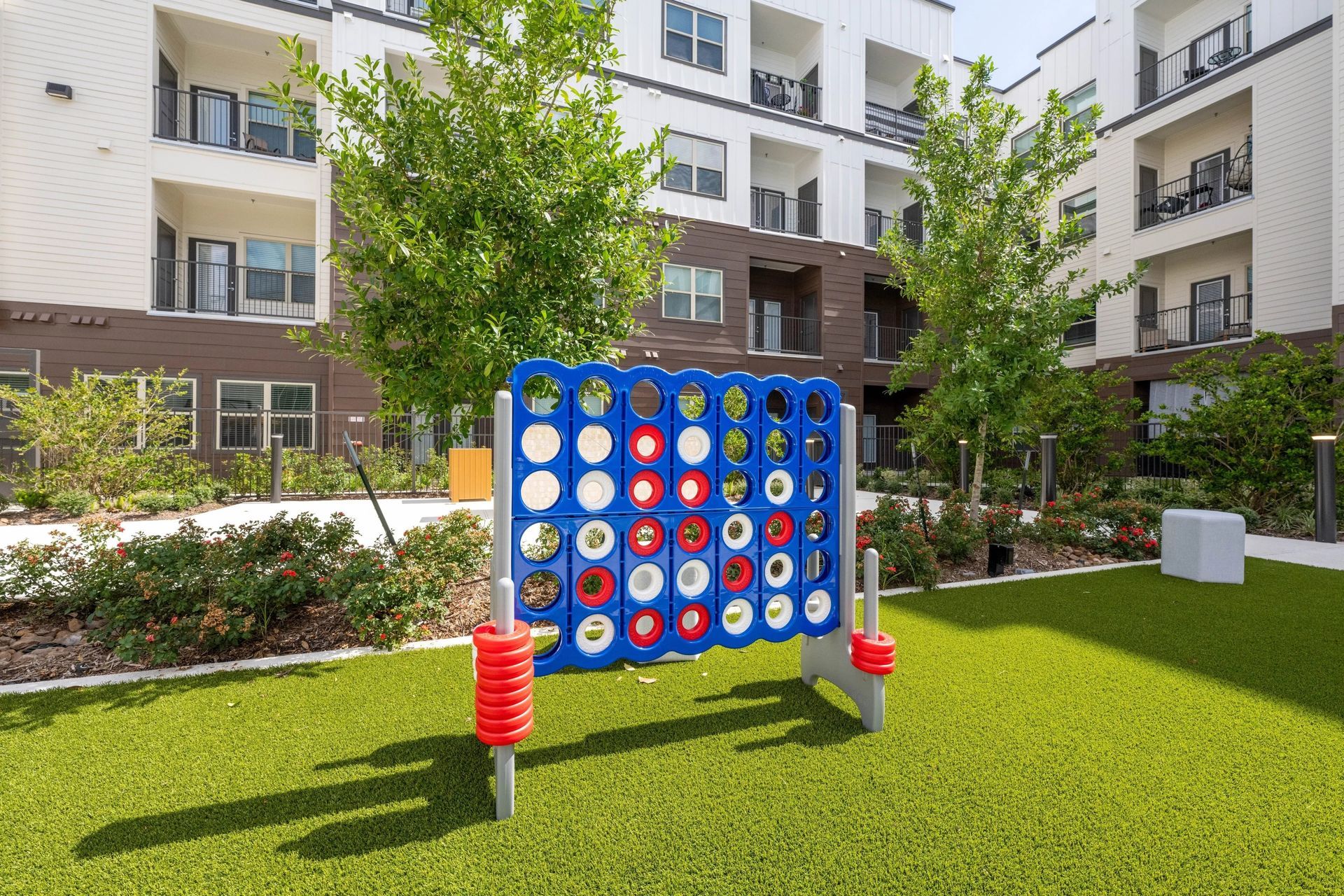 Outdoor giant Connect Four game on a lawn in front of apartment buildings.