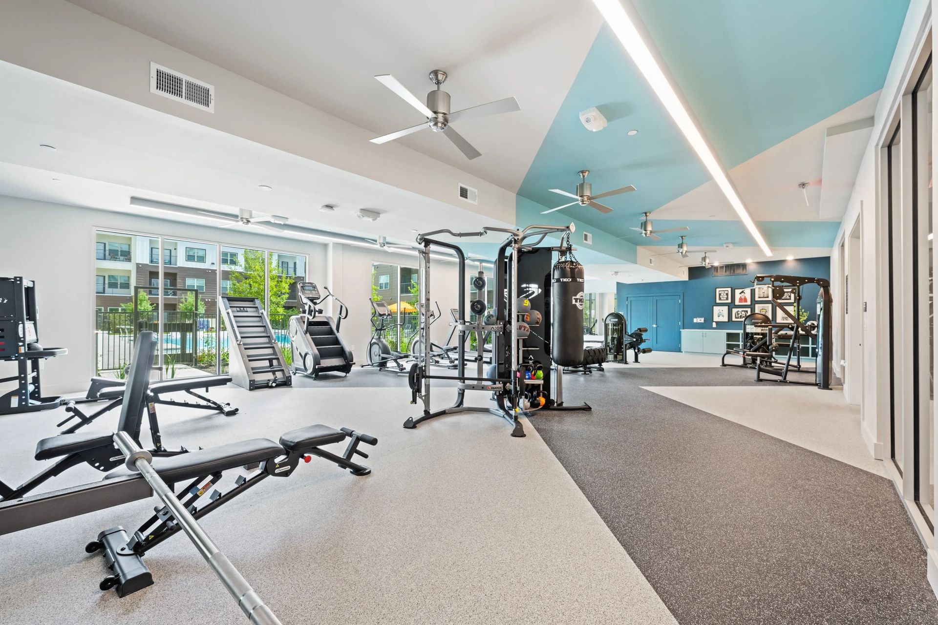 Modern gym interior with weight machines, benches, and mirrored walls under bright skylights