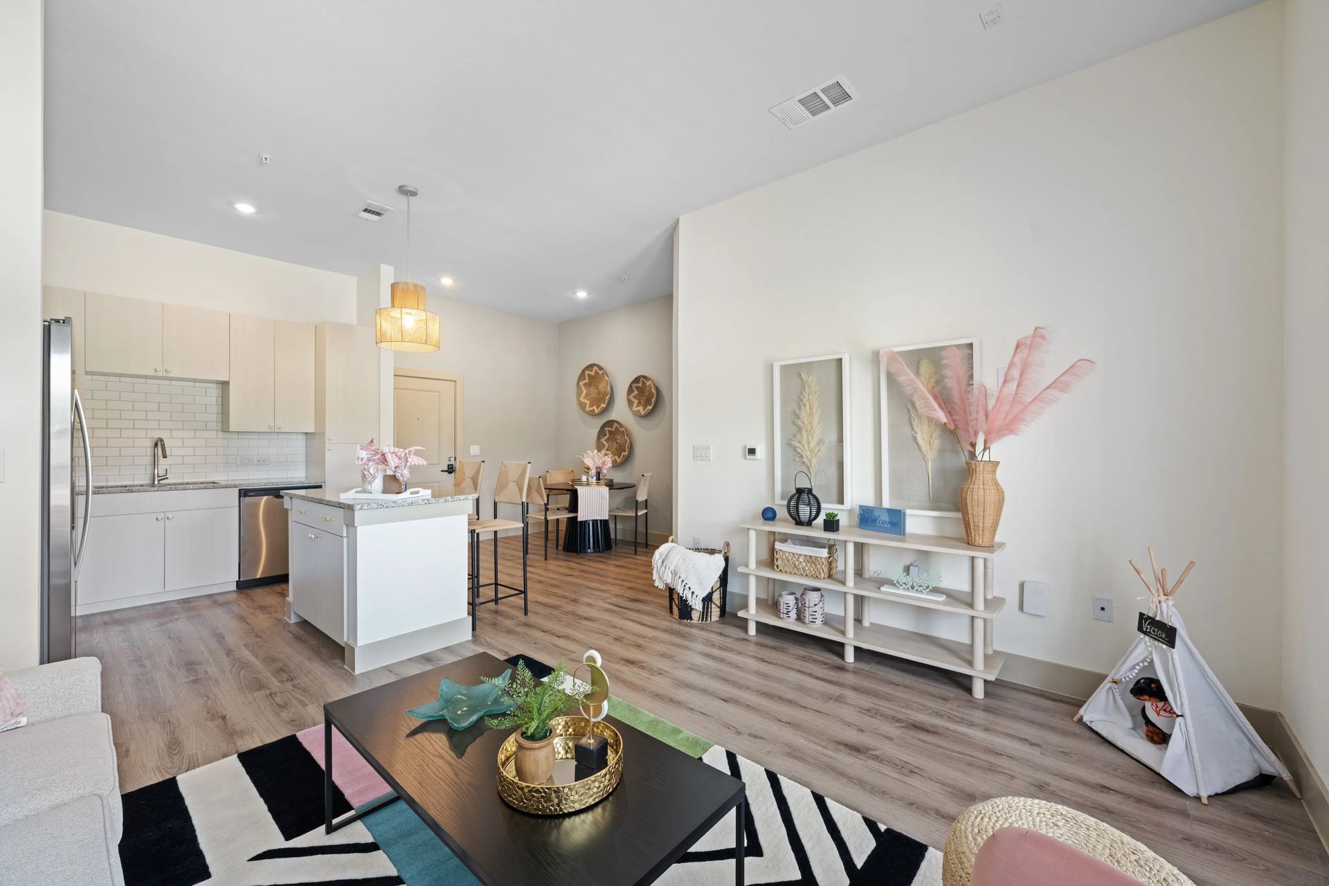 Bright open-concept living room and kitchen with white walls, wood floors, and modern decor.