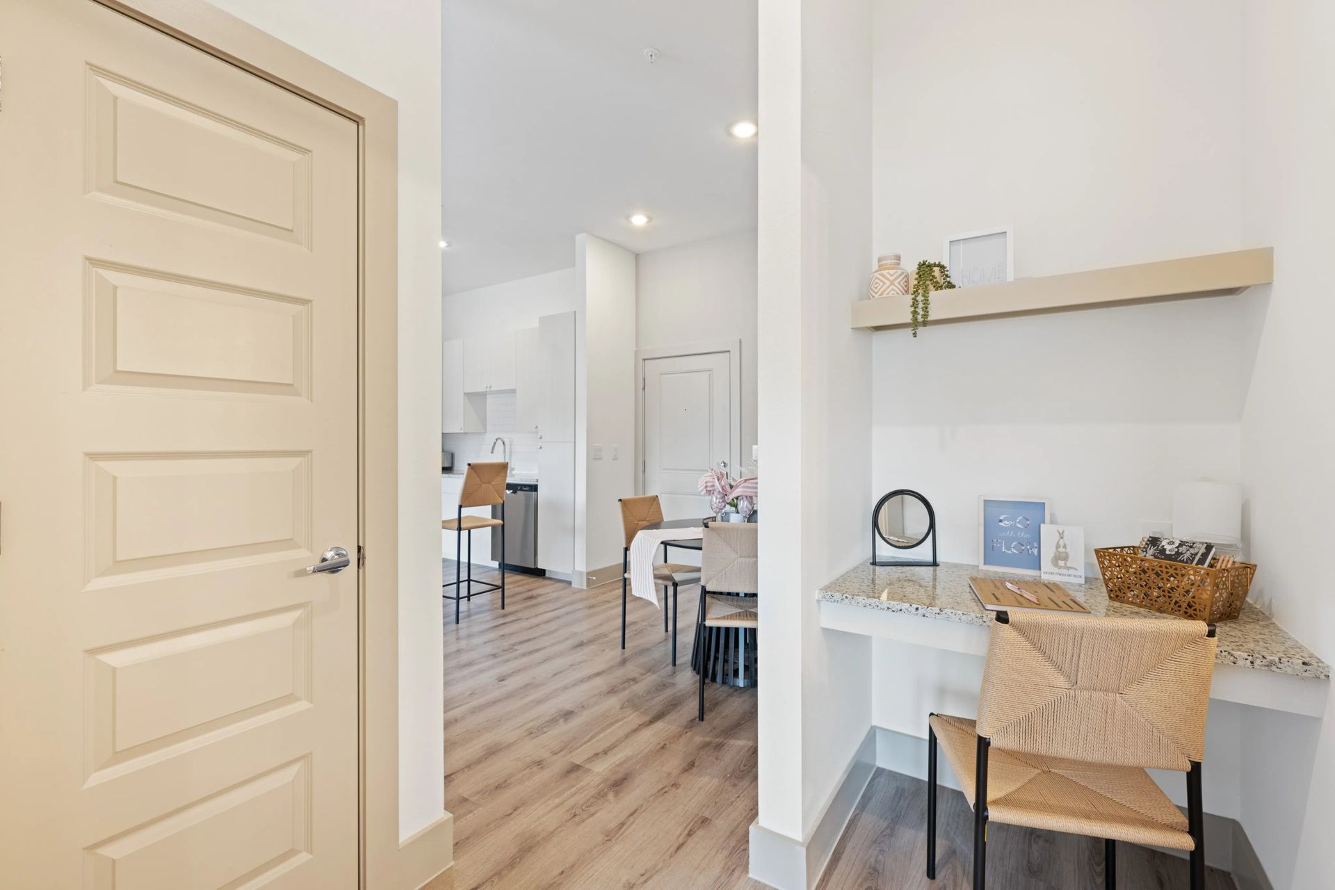 Bright hallway leading to a dining area, with a small desk nook and light wood floors.
