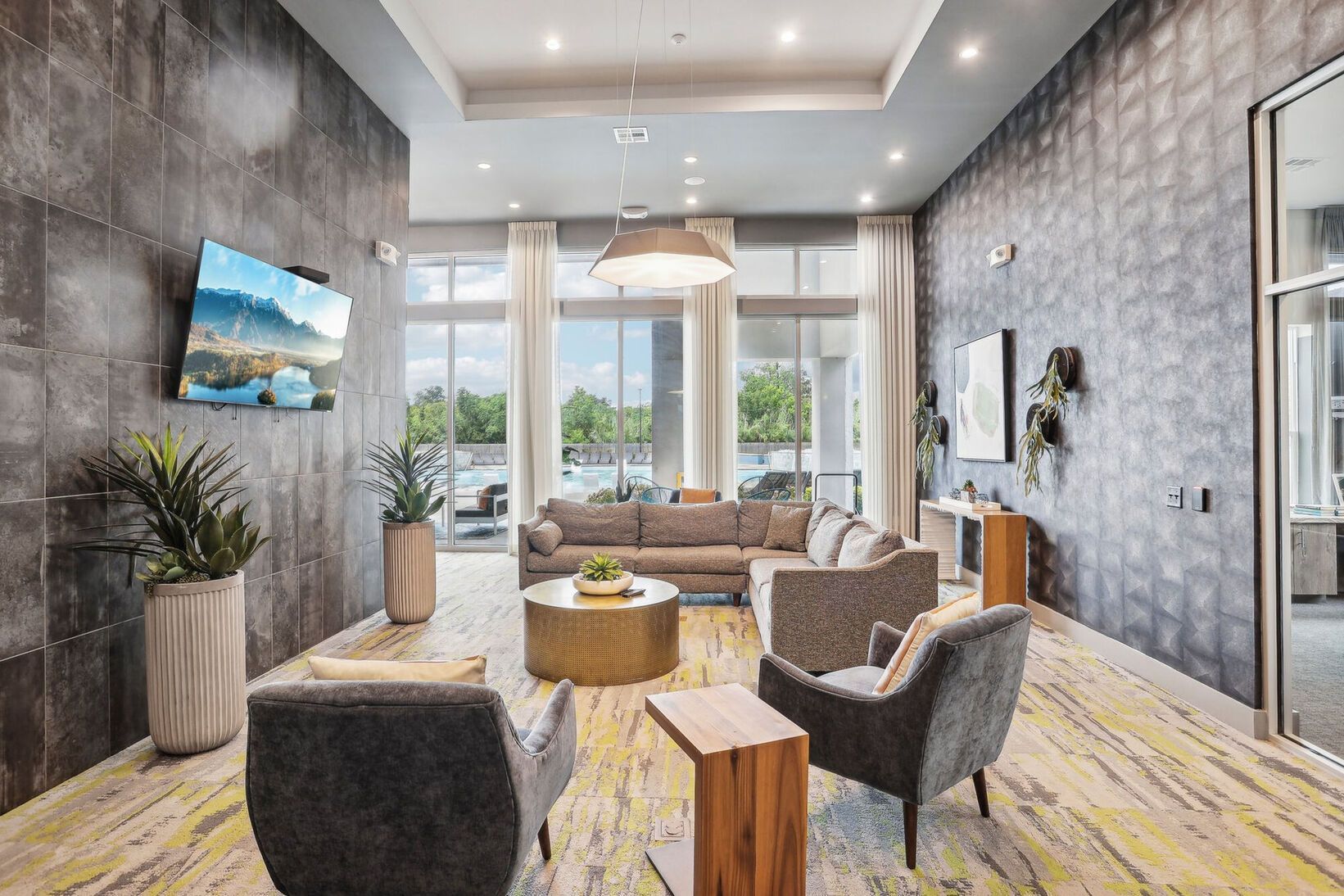 Modern living room with gray chairs, wood accents, large windows, and a city view