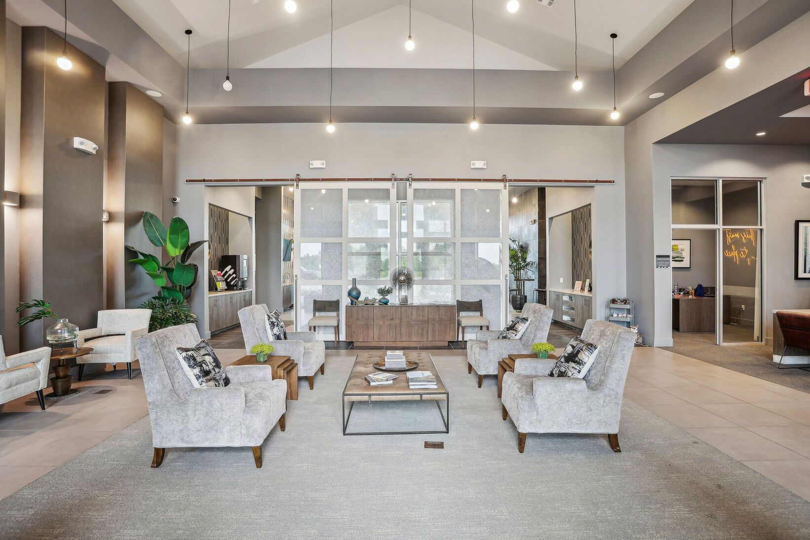 Modern apartment lobby with white chairs, glass coffee tables, and high ceilings