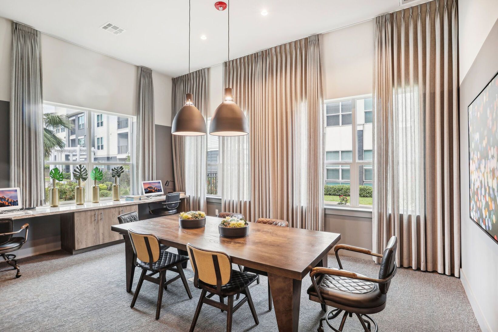 Modern dining room with wooden table, pendant lights, tall curtains, and large windows