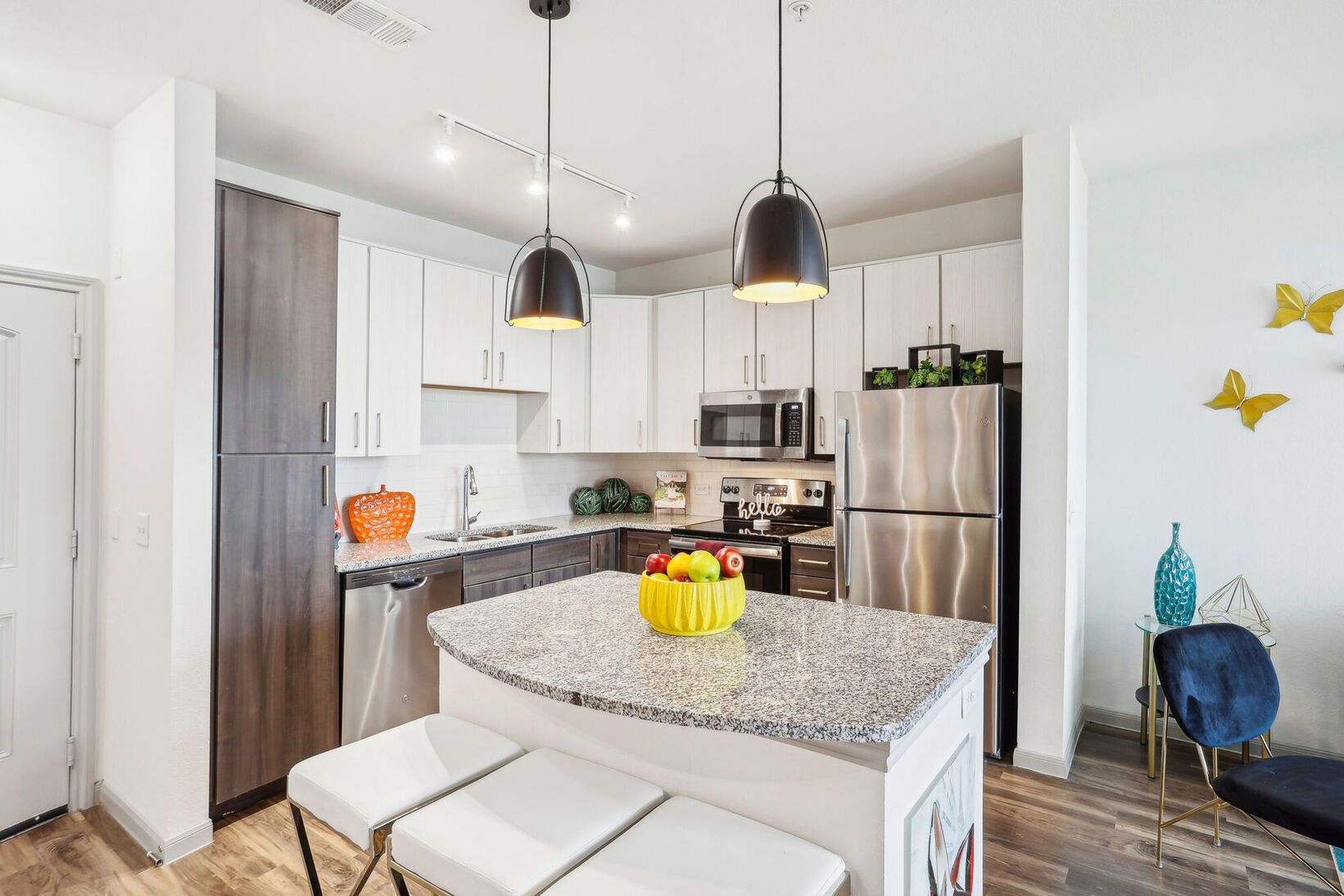 Modern kitchen with granite island, stainless steel appliances, pendant lights, and white cabinetry
