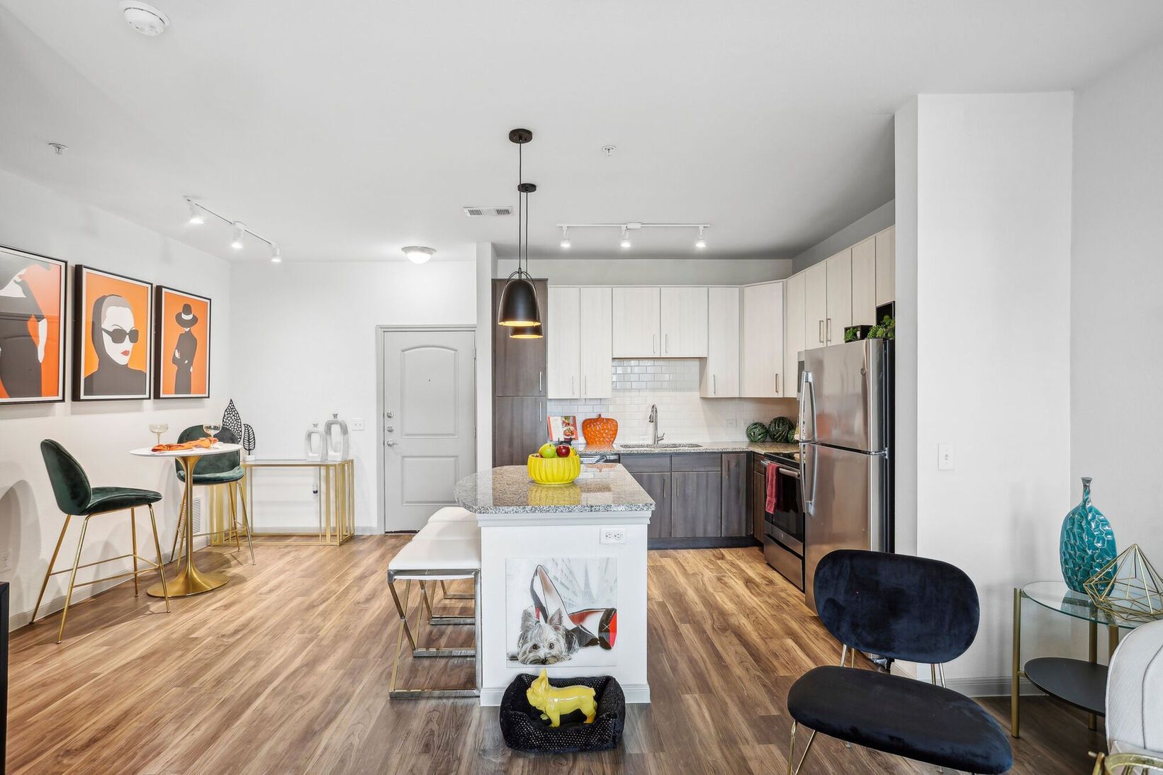 Modern open-plan kitchen with white cabinets, wood floors, island, and black chairs
