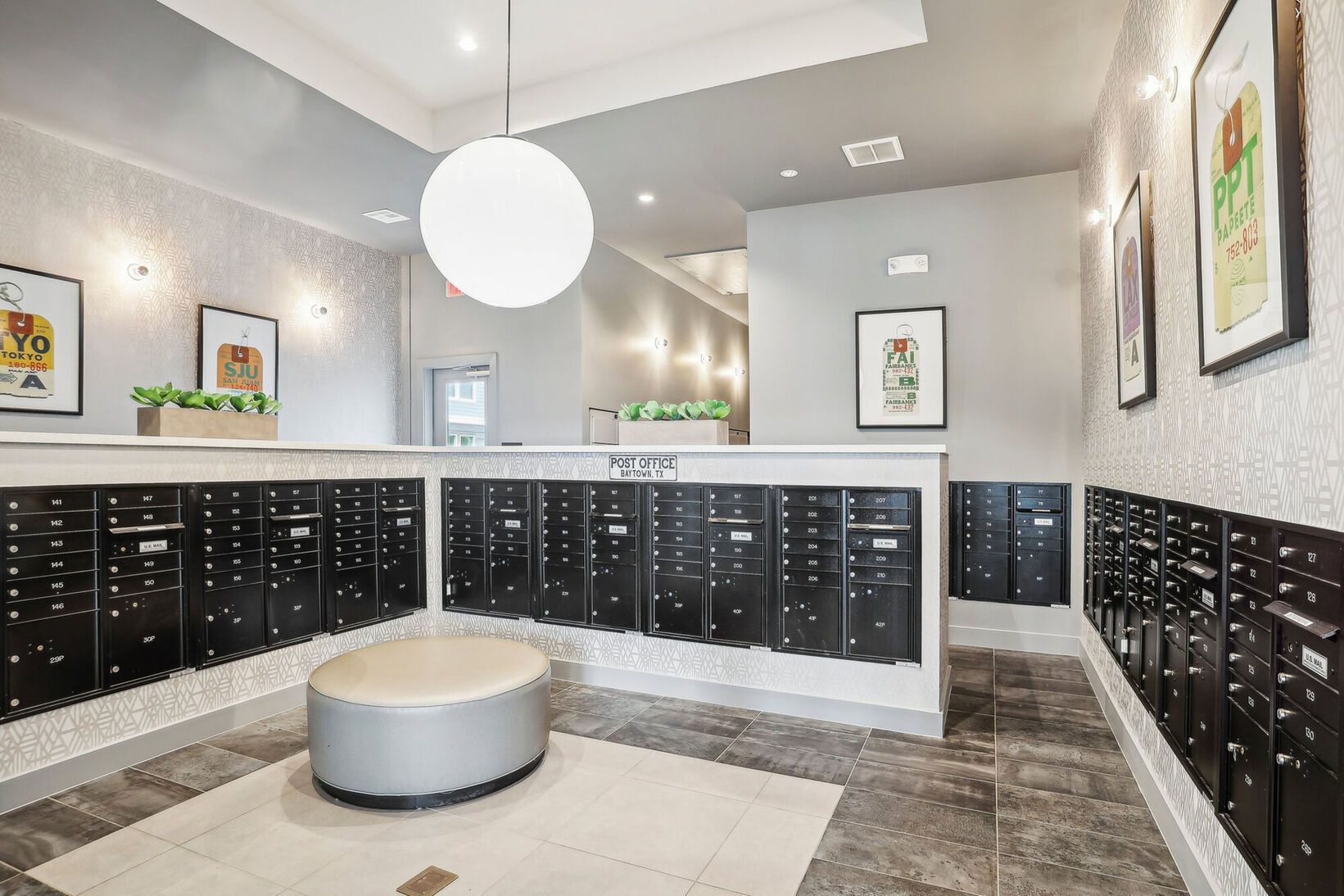 Modern apartment lobby with black mailboxes, white walls, and a round pendant light