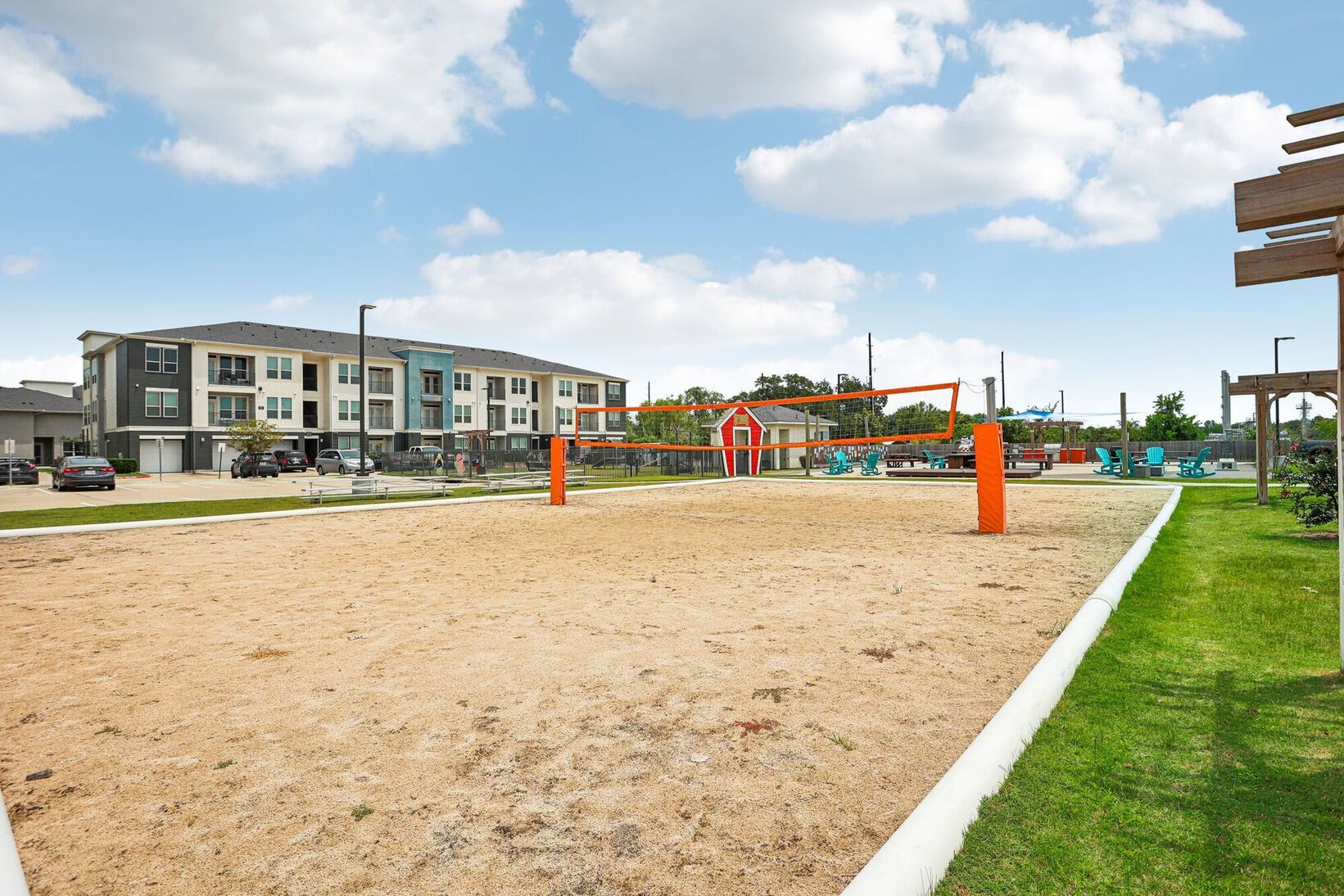 Sand volleyball court beside apartment buildings under a blue sky