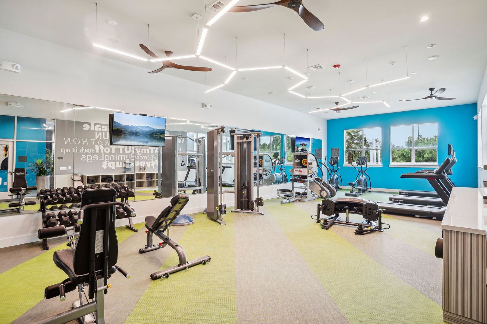 Bright modern gym with exercise machines, mirrors, and blue accent walls