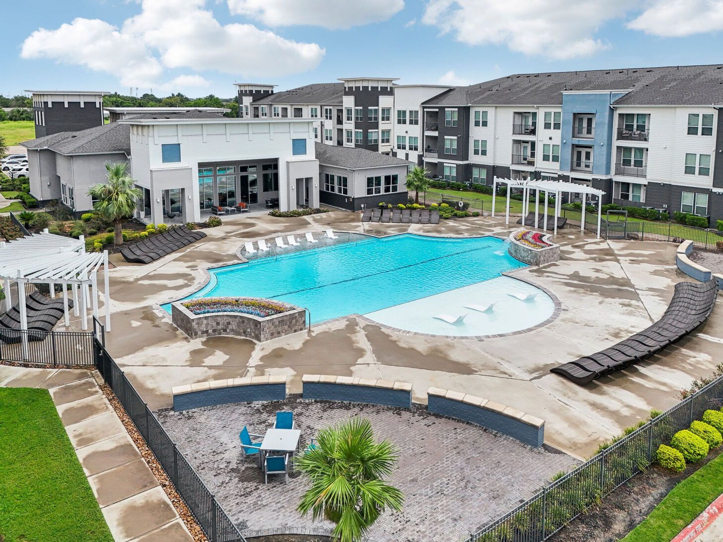 Apartment complex pool with lounge chairs and a white pergola courtyard
