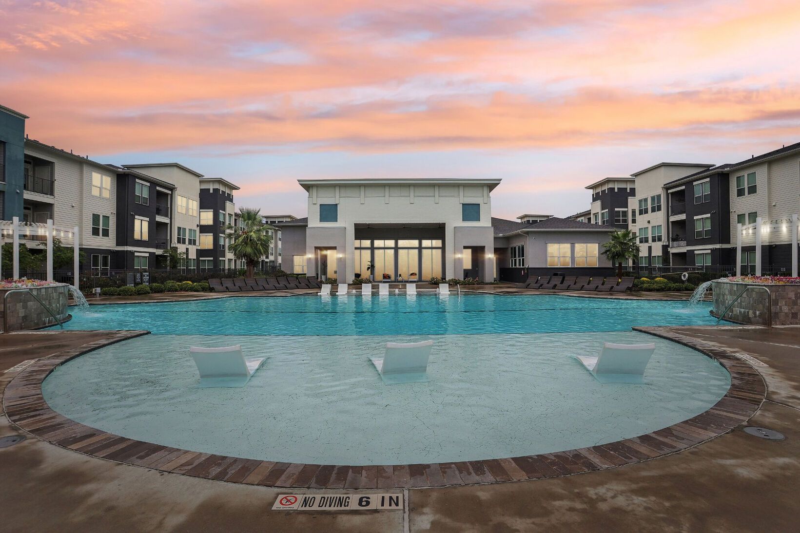 Modern apartment courtyard with a large swimming pool at sunset