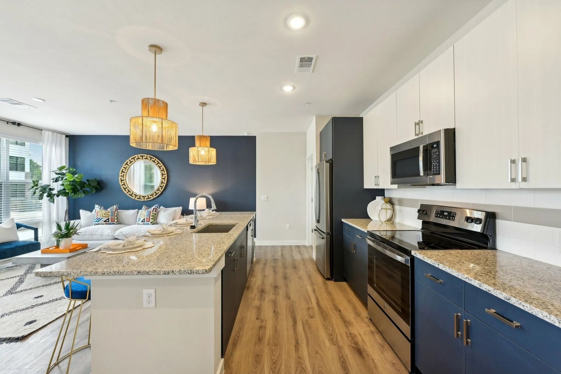Bright modern kitchen with white cabinets, granite island, navy lower cabinets, and wood flooring.