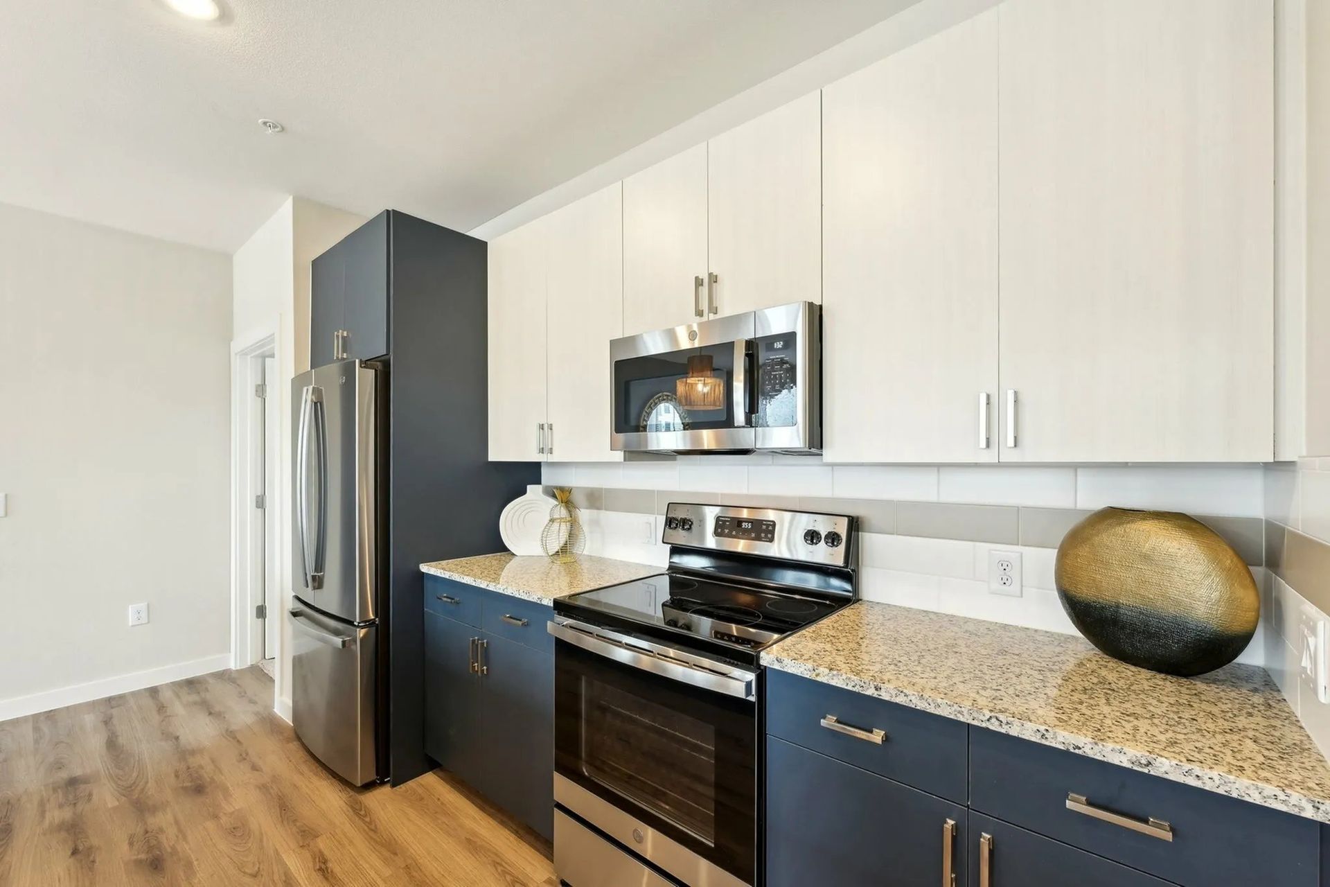 Modern kitchen with white cabinets, stainless steel appliances, granite countertops, and wood flooring