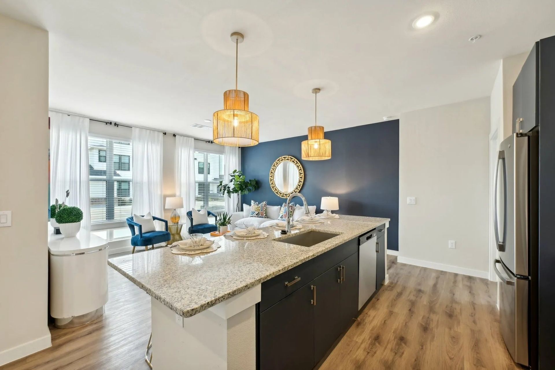 Bright modern kitchen with island, pendant lights, blue accent wall, and adjacent dining area with large windows