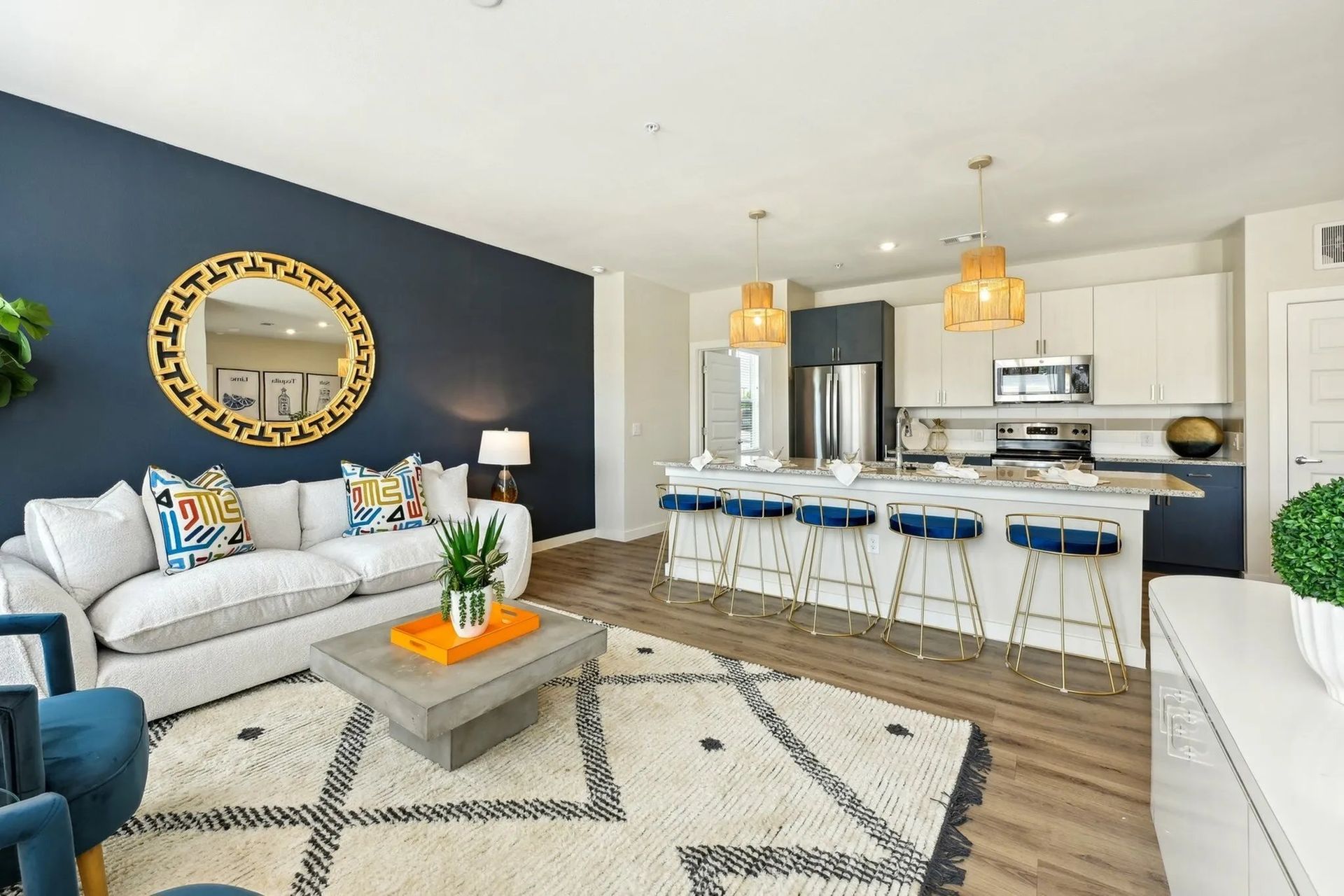 Bright modern living room with gray sofa, navy accent wall, kitchen island, and geometric rug
