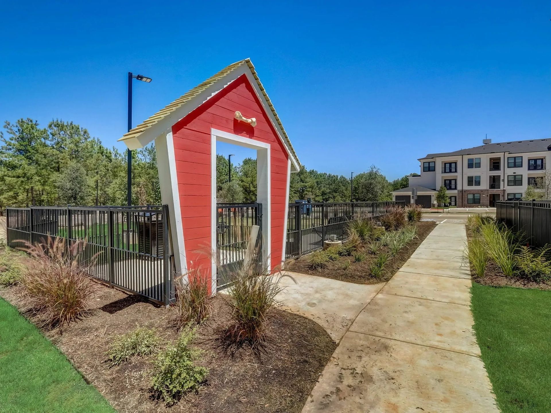Red-and-white garden structure beside a walkway in a landscaped apartment courtyard