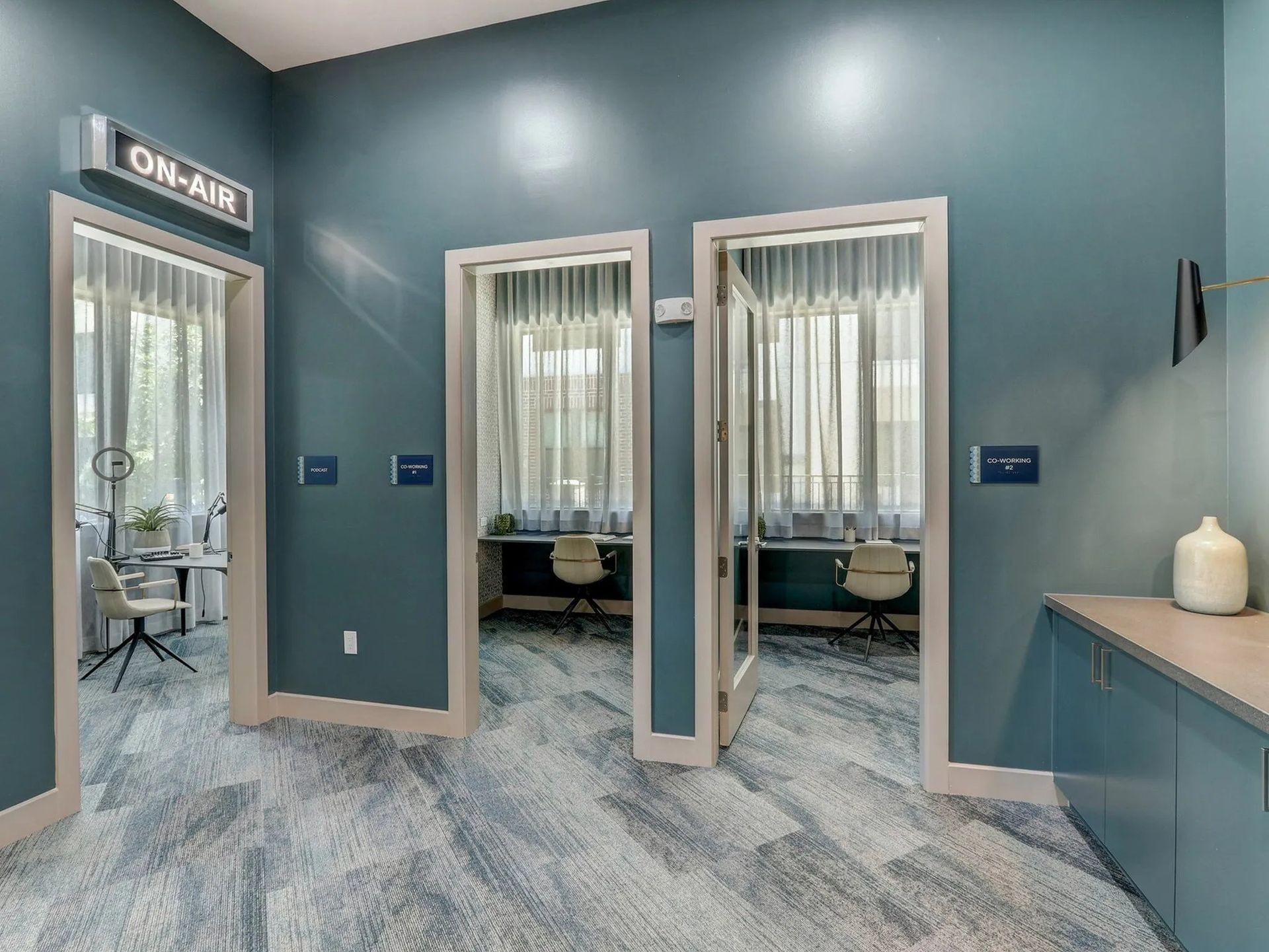 Modern medical office with blue walls, open doorways, and exam rooms visible through glass curtains.