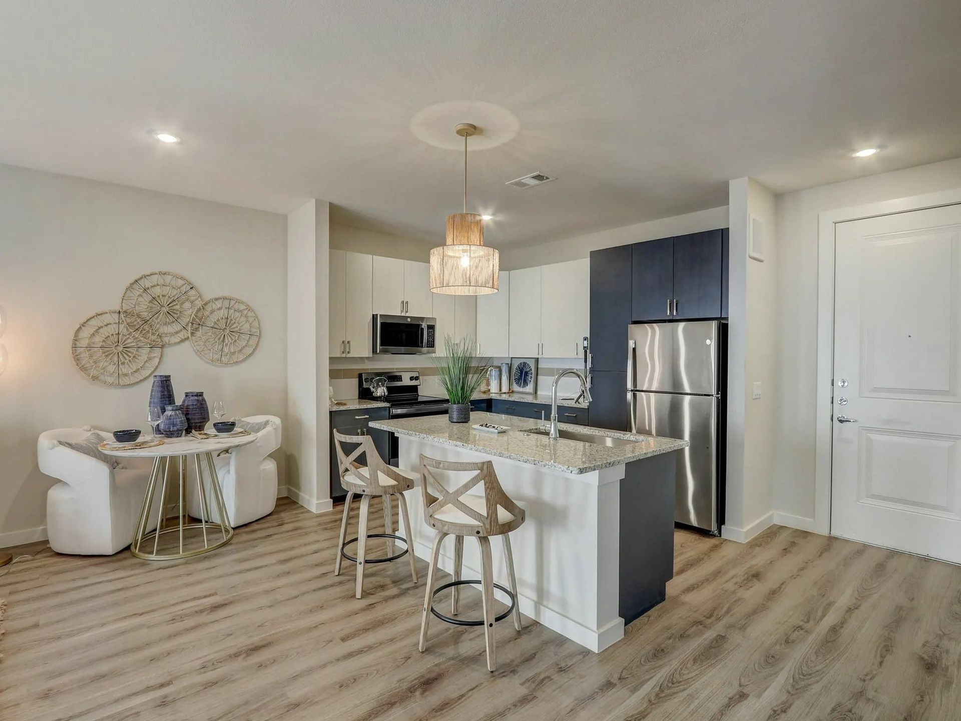 Bright kitchen and dining area with white cabinets, gray island stools, and light wood flooring