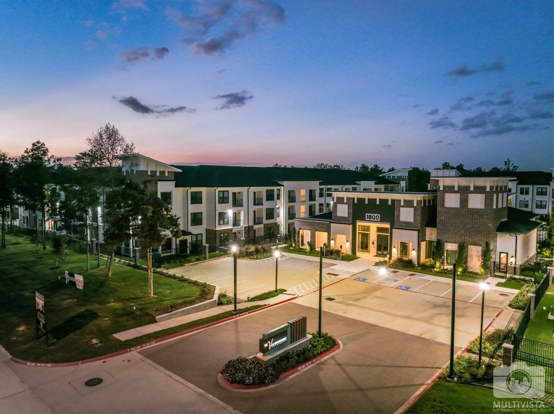 Modern campus building at dusk with lit windows, landscaped courtyard, and pathways under a blue evening sky