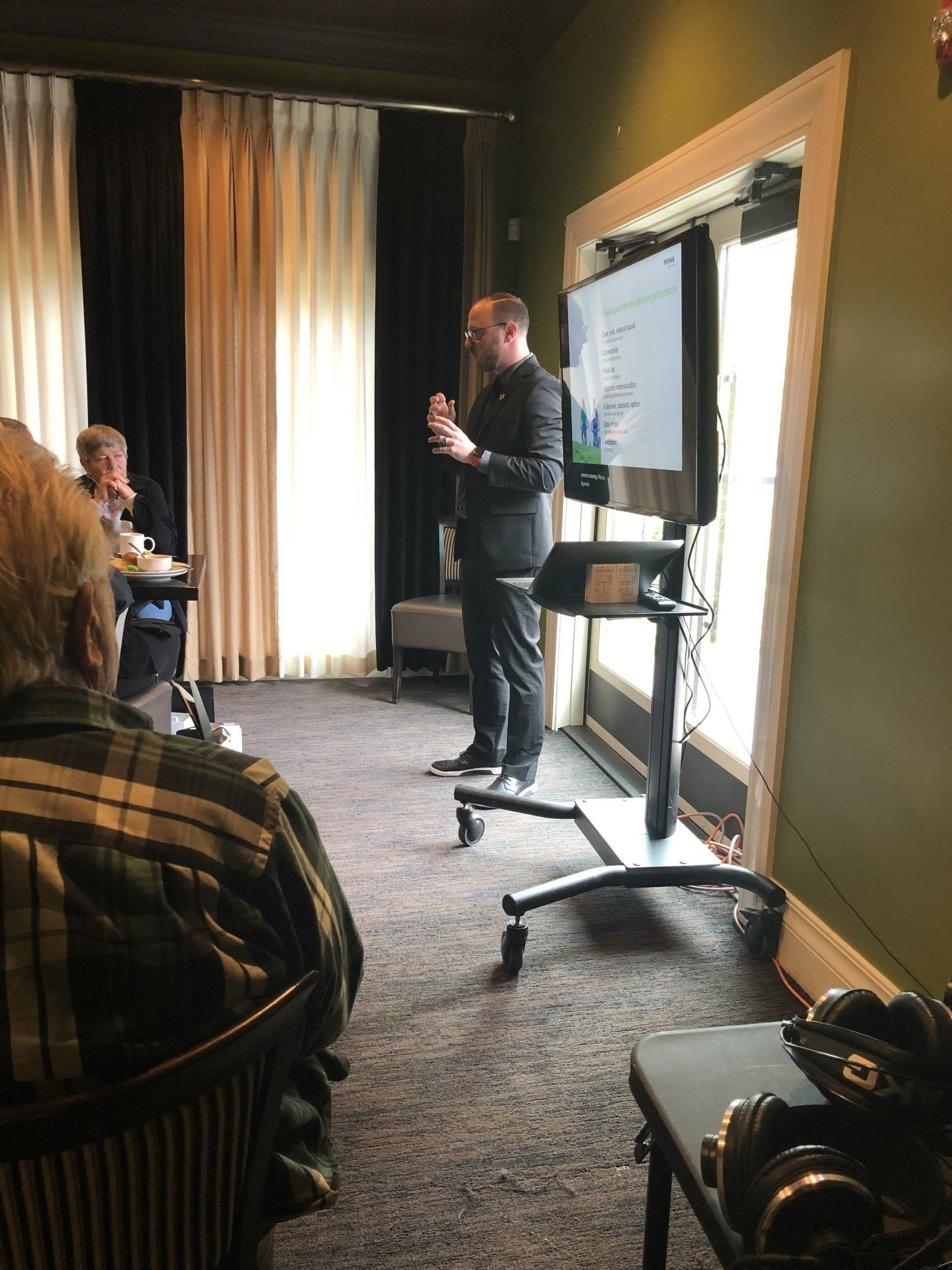 A hearing specialist giving a presentation to a group of people in a room.