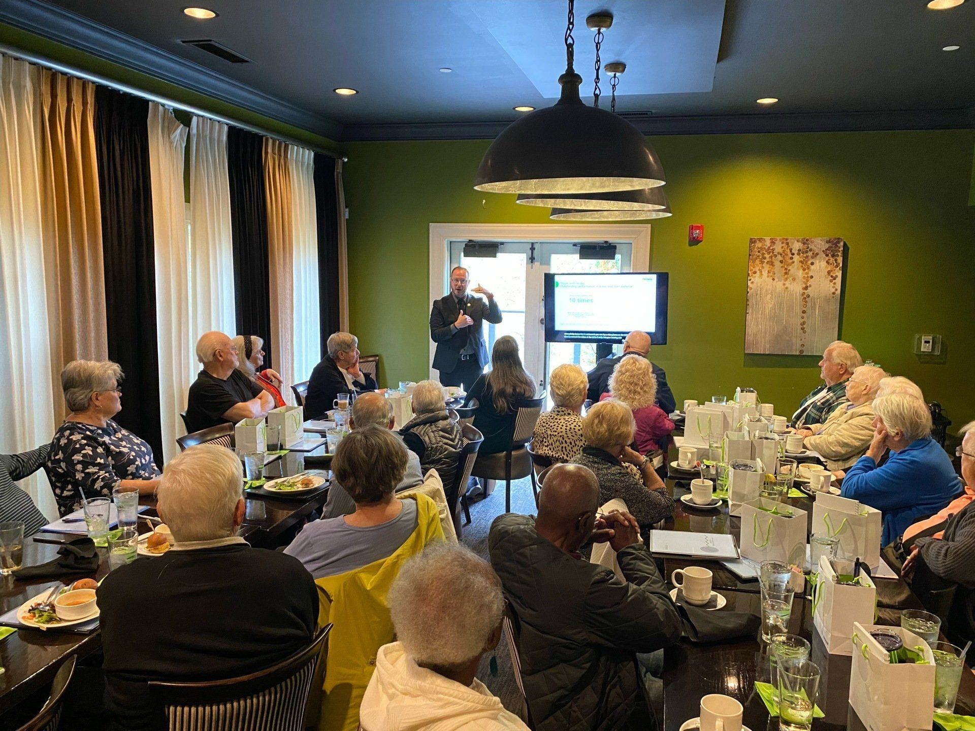 A group of people are sitting at tables in a room watching a presentation.