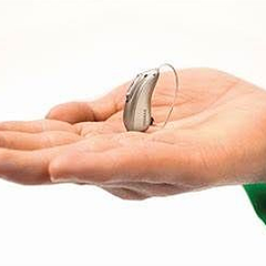 a person is holding a hearing aid in their hand