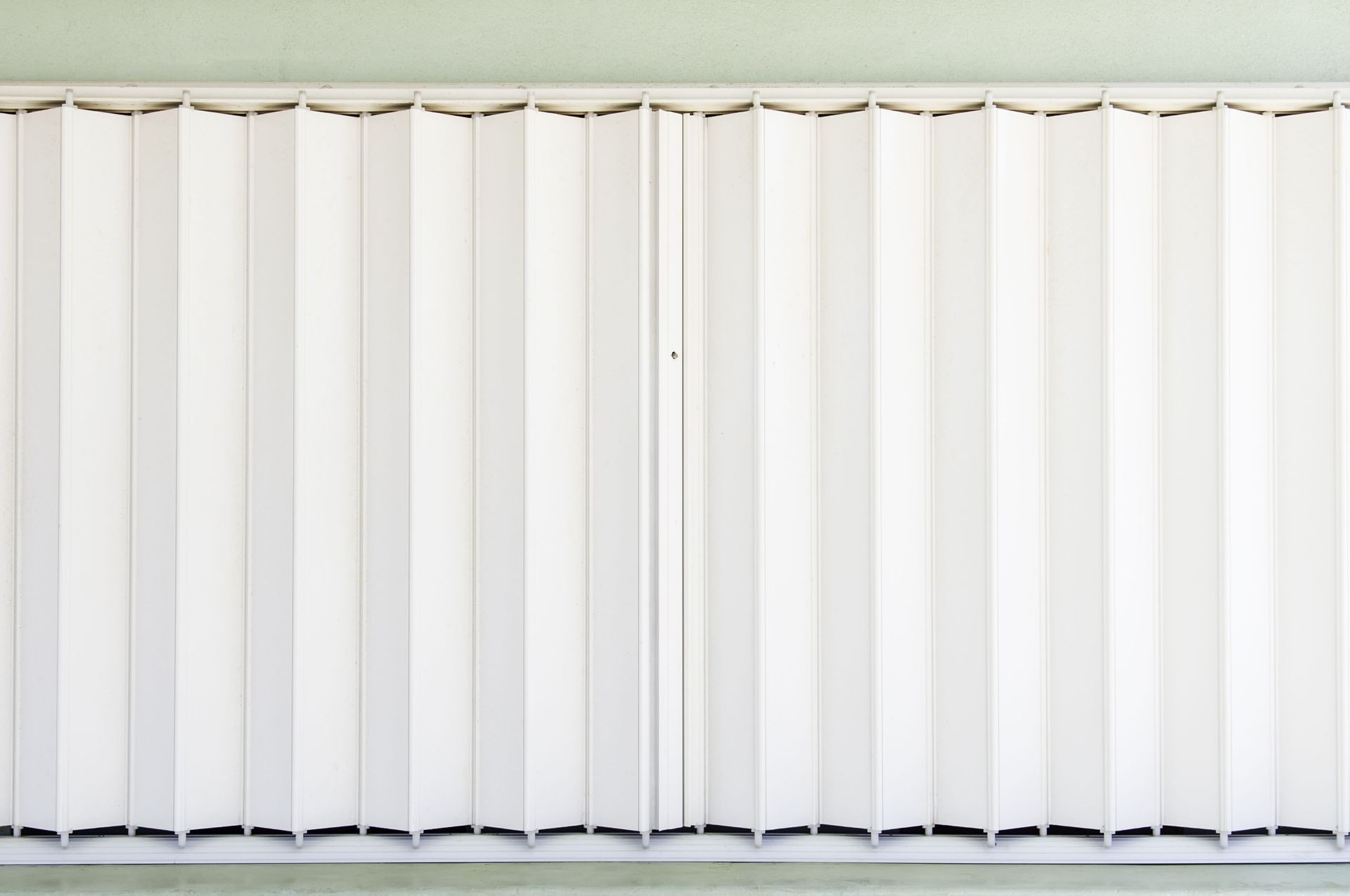 A white folding accordion door panel fully extended against a wall.