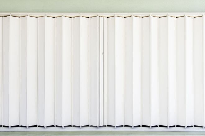 A white folding accordion door panel fully extended against a wall.