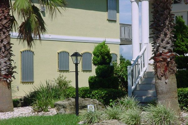 Yellow building with palm trees and a black lamp post in front.
