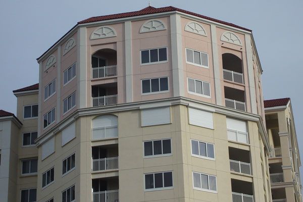 Multi-story building with beige and pink sections, balconies, and many windows.