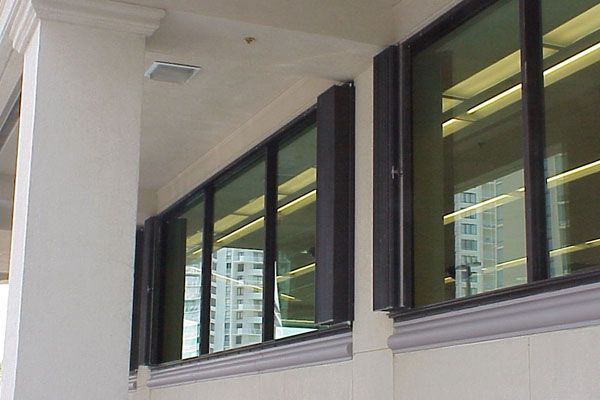 Exterior view of a building with large rectangular windows reflecting a city skyline, framed by a white column.