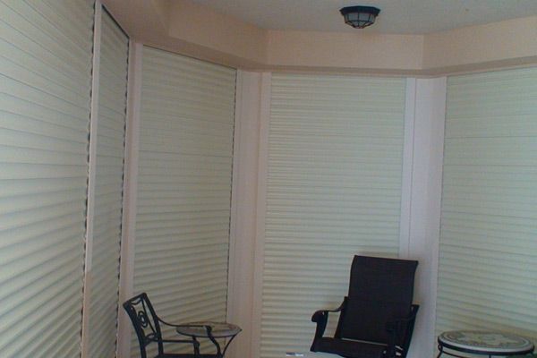 Interior corner of room with light-colored blinds, two chairs, and a light fixture.