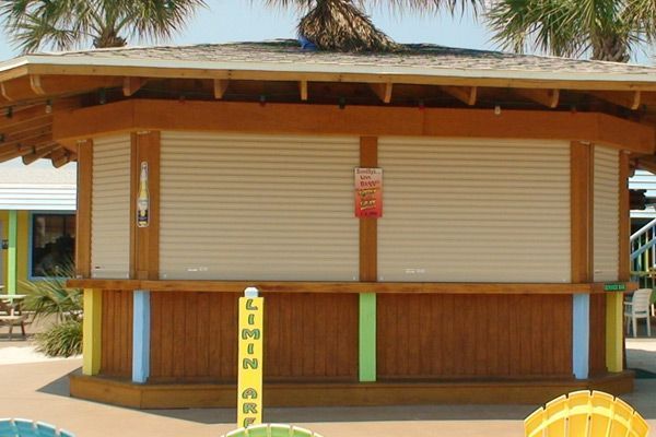Tiki bar with tan shutters, wooden beams, and colorful vertical supports.