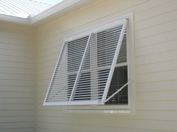 White louvered window open, attached to a beige house exterior.