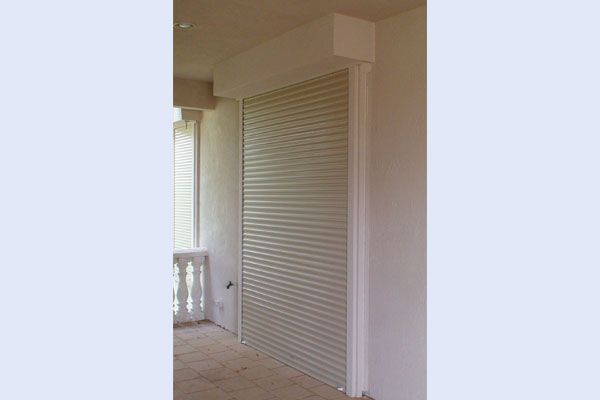 Closed, beige roll-up security shutter on a building's exterior.