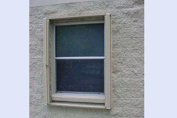 Window with beige frame and screen on a textured, light-colored wall.