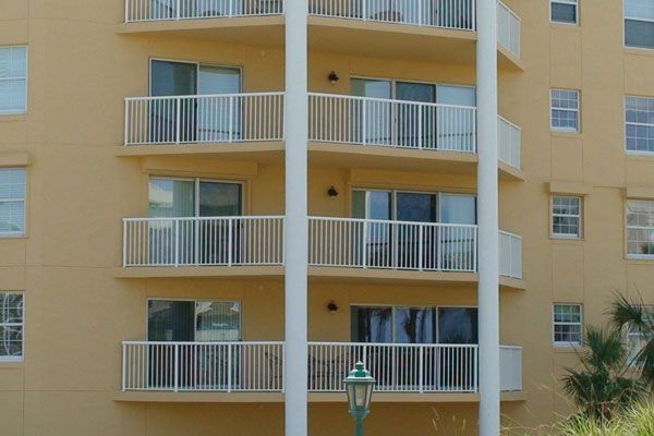 Tan apartment building with balconies and white railings.