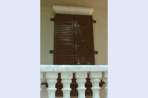 Brown shuttered window above a white balustrade.