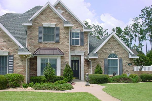 Brick house with gray shutters, front door, and manicured lawn.