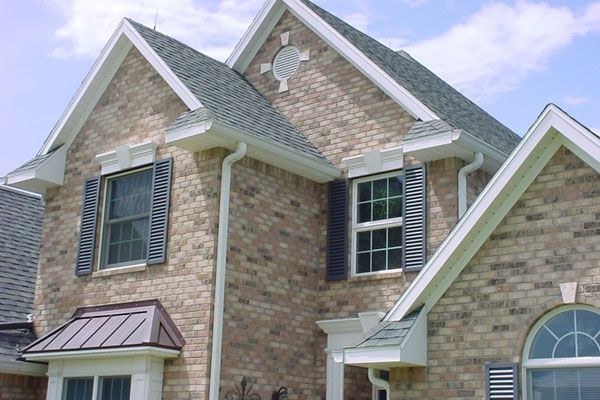 Two-story brick house with gray roof, white trim, and dark blue shutters.