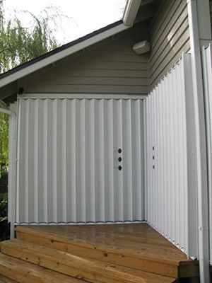 White corrugated metal enclosure on a wooden deck attached to a building's exterior.