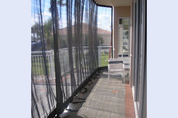 Patio with black privacy screens, a white chair, and a tiled floor.