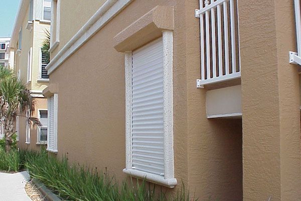 Beige building with white shuttered window, balcony.
