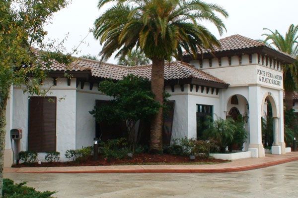 Spanish-style building with red-tiled roof, palm tree, and sign reading 