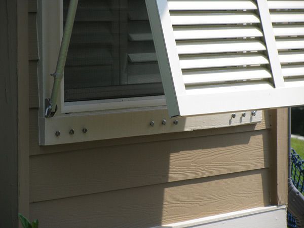 Window with white shutter open, beige siding.