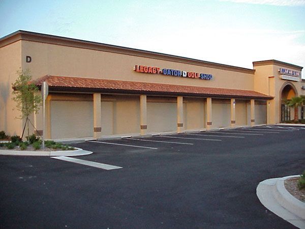 Exterior of Legacy Jewelry and Coin Shop, beige building with closed storefront shutters, parking lot.