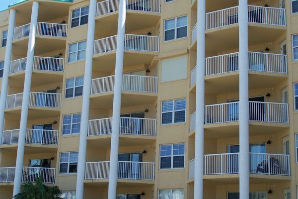 Yellow apartment building with white balconies and support columns.