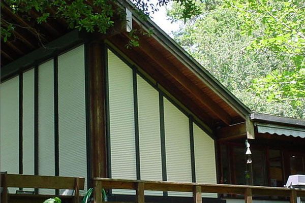 Angled building with light-colored slatted siding, dark trim, and wooden deck.
